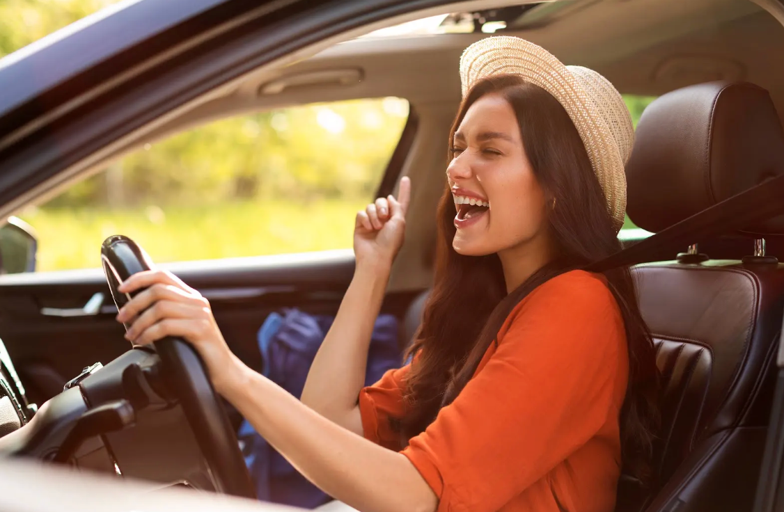 Woman singing along to music while driving.